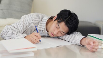 勉強しながら寝るアジア人男性 © mapo