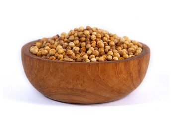 A wooden bowl filled with whole coriander seeds, a key aromatic spice in cooking. The healthy and natural ingredient is isolated on a clean white background.