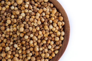 Top-down view of whole, dried coriander seeds in a rustic wooden bowl, isolated on a white background. An essential aromatic spice for cooking and culinary concepts.