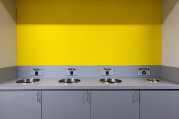 yellow wall and cabinet with openings for trash disposal