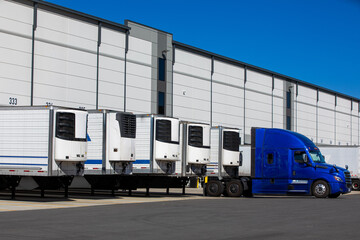 parked refrigerated semi truck trailers in cold storage warehouse