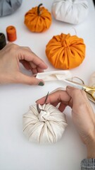 Hands crafting fabric pumpkins
