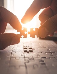 Hands joining puzzle pieces, sunlight