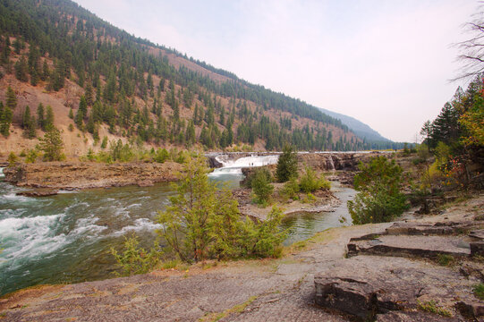 Rugged River Canyon With Turquoise Water And Forested Cliffs – Hiking Overlook Scene. Kootenai National Forest in Montana. Carves a canyon through rocky cliffs, framed by pine trees. Hikers on a ridge - Powered by Adobe