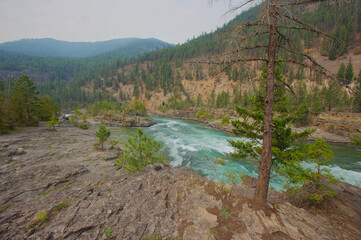 Rugged River Canyon With Turquoise Water And Forested Cliffs – Hiking Overlook Scene. Kootenai National Forest in Montana. Carves a canyon through rocky cliffs, framed by pine trees. Hikers on a ridge