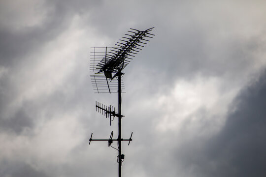 A complex television antenna array is silhouetted against a cloudy, overcast sky.