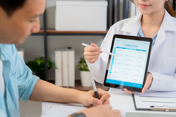 Close up nutritionist using tablet to explaining personalized meal plan with AI to patient during healthcare consultation, healthy lifestyle, woman dietitian showing nutrition plan with AI on tablet. © NT_studio
