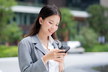 Young asian businesswoman using chatbot or AI message on smartphone outdoors in city, business woman chat on smart phone with AI assistant in urban, artificial intelligence, technology and business.