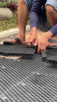 Person Installing Interlocking Plastic Pavers on Garden Pathway Outdoor Daylight
