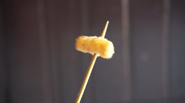 French fries skewered on a wooden stick with a brown background