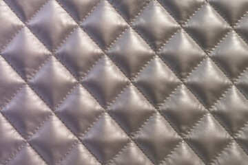 Obraz premium Luxurious quilted satin fabric texture with elegant diamond pattern and soft padded surface