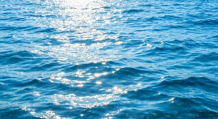 Blue ocean water reflects sunlight creating sparkling patterns on the surface