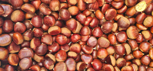 Fresh chestnuts with rich brown shells fill the frame in a colorful display at a local Granada market, ready for roasting or cooking. autumn produce
