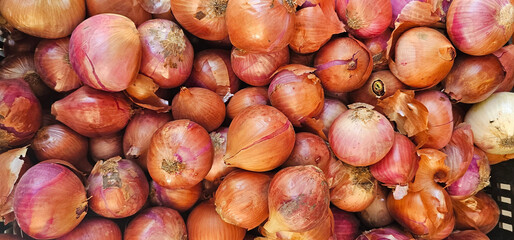 Fresh red onions with papery skins on display at a market in Granada, Spain. Natural light highlights their rustic texture. vegetables, market