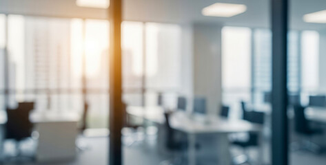 Blurred modern office interior with bright window light and furniture shapes, showing silhouettes of desks and chairs, creating a soft focus atmosphere of productivity and creativity.