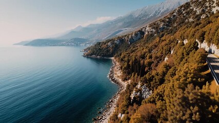 Exhilarating aerial travel adventure with modern car on its scenic coastal road journey beside majestic mountains and calm sea