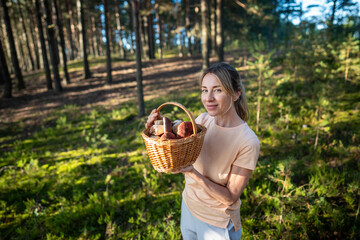 Proud happy woman presenting basket full of prized porcini mushrooms boletus. Successful female...