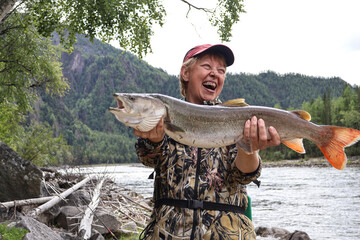 Surprised joy: woman amazed by her taimen (Hucho taimen) trophy catch