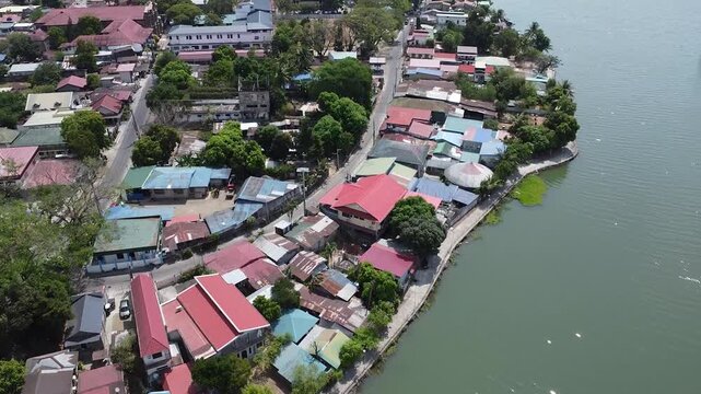 Forward Drone Flight Over Barangay Near Lake in San Rafael Bulacan, Philippines &mdash; Aerial 4K Footage Showing Houses, Fields, and Water Reflection Under Clear Blue Sky