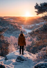 Woman gazes at breathtaking golden hour sunrise over snow covered winter landscape from mountain peak