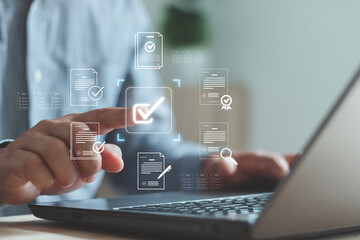 Businessman using laptop with virtual document checklist icon, representing digital approval, online form submission, task management and workflow automation in modern technology.