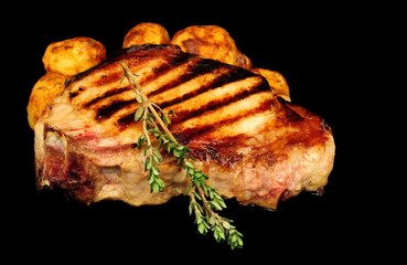 Grilled pork chop steak with seared griddle lines on a black background