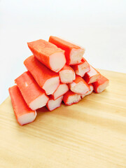 Fresh Cooked Crab Sticks Scattered Randomly on a Cutting Board Against White