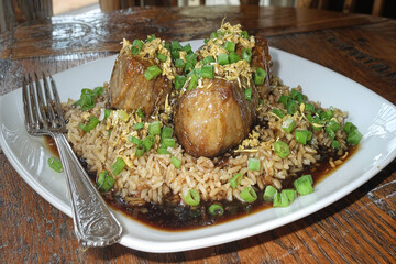 White rice with tender meat and herbs on a square plate. Elegant Asian cuisine.