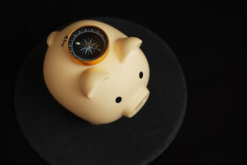 Piggy Bank with Compass on Dark Background: Symbolizing Financial Direction and Savings Guidance