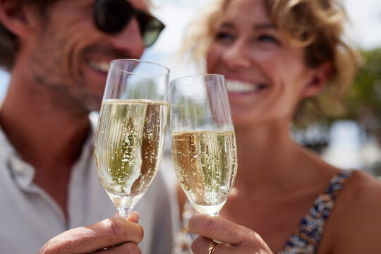 Happy couple celebrating engagement with champagne outdoors