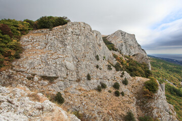 Rocky mountain slope with sea view in autumn under cloudy sky, natural landscape and scenic panorama