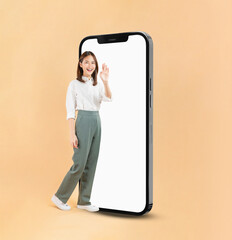 Happy Asian business woman hand touching a large smartphone screen isolated on beige color background, travel concept.