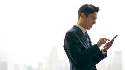 都市を背景にスマホを使う男性ビジネスパーソン © metamorworks