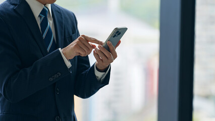 オフィスでスマホを使うビジネスパーソン