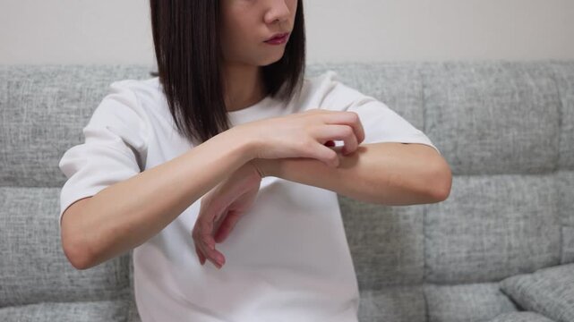 Zoom-out shot of a woman scratching her arm due to dermatitis