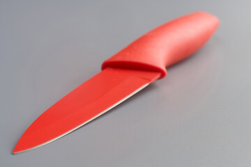 Modern red kitchen knife with silicone handle and color blade on a smooth grey background, minimal look with copy space for branding or text, high‑resolution close‑up. Photo
