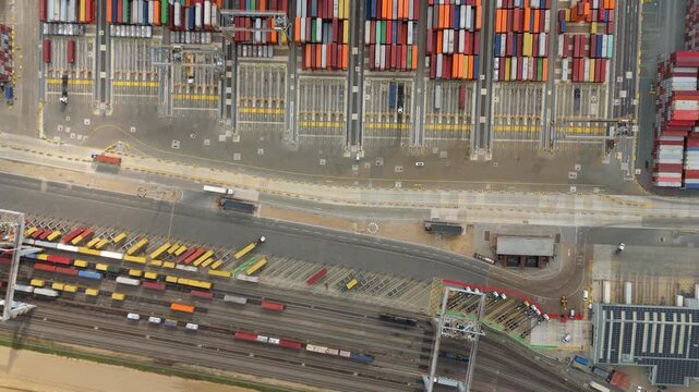 Top down aerial drone view of busy shipping port containers and cranes moving cargo onto tankers and ships near London, United Kingdom. International port operations and logistics. 