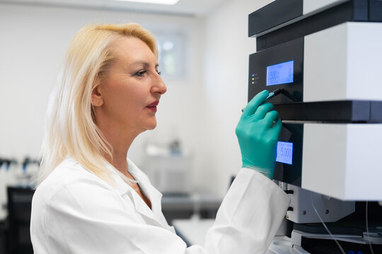 Scientist in lab coat using high-performance liquid chromatography instrument for precise analytical chemistry research. - Powered by Adobe