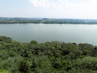 cenic view of a lake surrounded by lush greenery under a bright sky