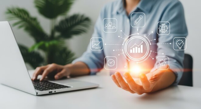 Person using laptop with glowing digital infographic icons hovering over hand business technology