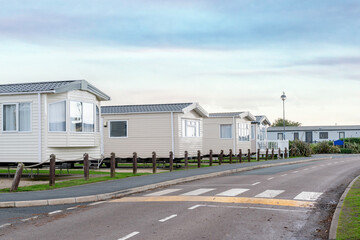Temporary homes line a quiet road at a holiday park during early morning light