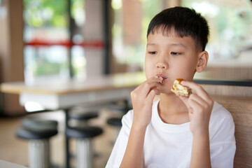 young boy is eating a sandwich, Asian boy is happily eating food