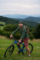 Obraz premium miling mature man with bicycle enjoying countryside ride at sunset.