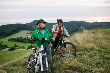 Fototapete Rund Extremsportarten Older couple cycling together in nature, smiling and enjoying outdoor adventure.  © Halfpoint