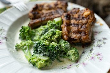 Cooked, steamed broccoli in a cream sauce and grilled pork ribs.