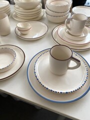Ceramic tableware with minimalist design on display, featuring plates, bowls, and mugs