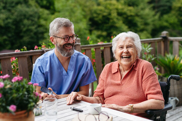 Nurse helping elderly woman measure blood sugar with glucometer.