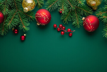 Merry Christmas and Happy Holidays greeting card, frame, banner. New Year. Noel. Golden and red Christmas ornaments on green background top view. Winter xmas holiday theme. Christmas tree decoration.