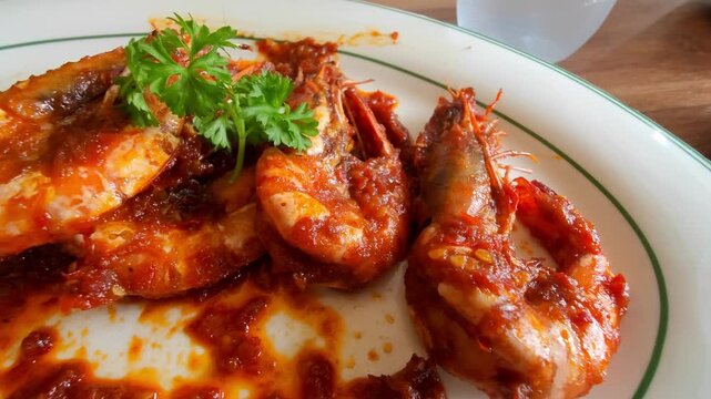 Close-up of Indonesian-style spicy shrimp cooked with chili sauce and served on a white plate. The dish is a popular seafood menu in Indonesian restaurants, known for its rich flavor and bright red 