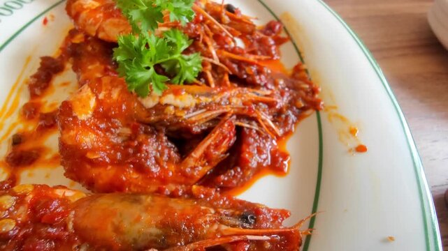 Close-up of Indonesian-style spicy shrimp cooked with chili sauce and served on a white plate. The dish is a popular seafood menu in Indonesian restaurants, known for its rich flavor and bright red 